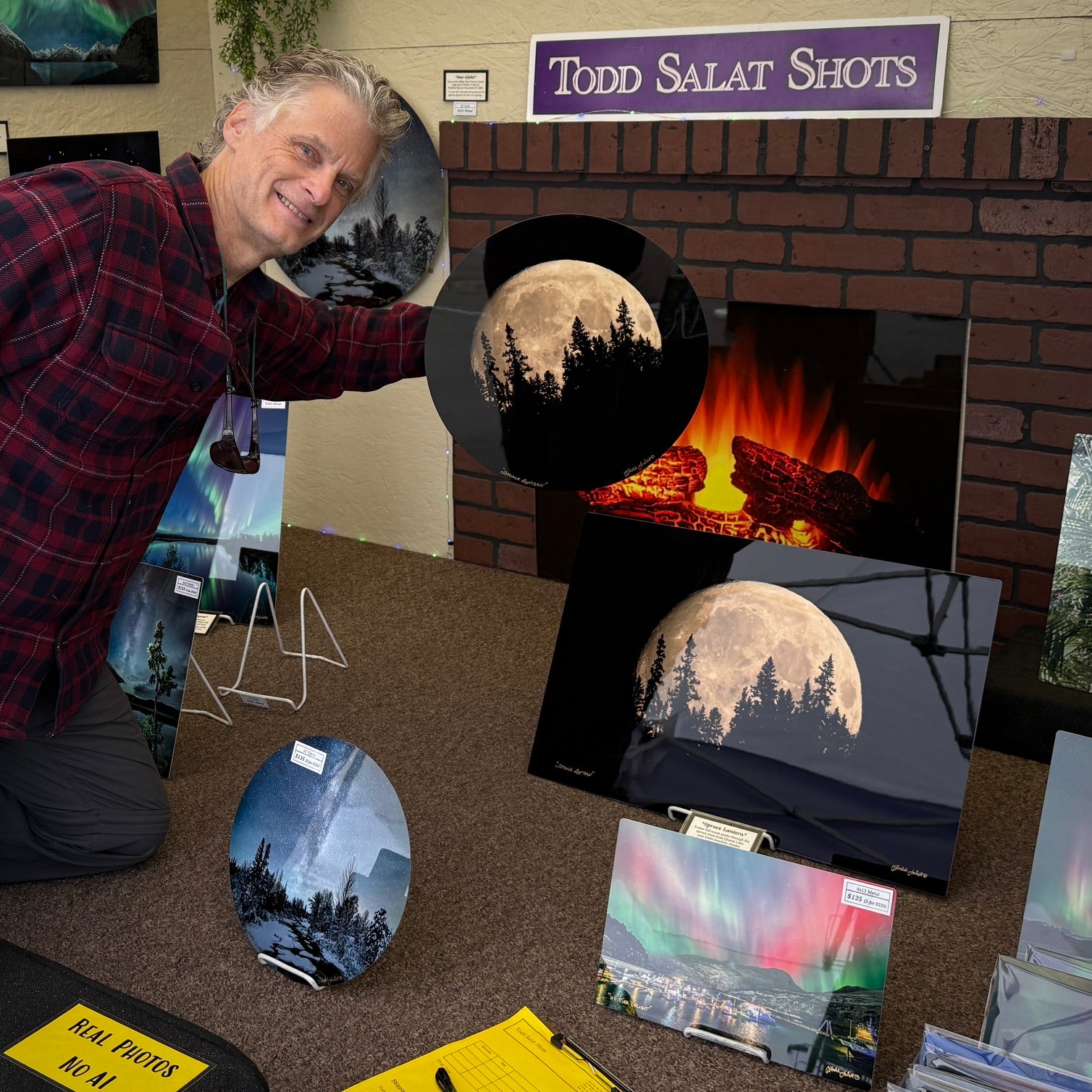 A display of custom photo prints and wall art, including spruce lantern, a fireplace scene, and northern lights artwork